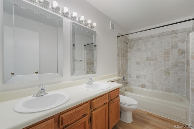 full bathroom with toilet, hardwood / wood-style floors, vanity, and tiled shower / bath combo