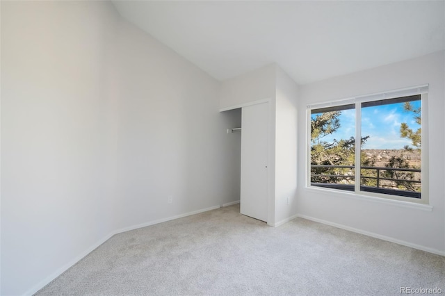 unfurnished bedroom with a closet, light colored carpet, and vaulted ceiling