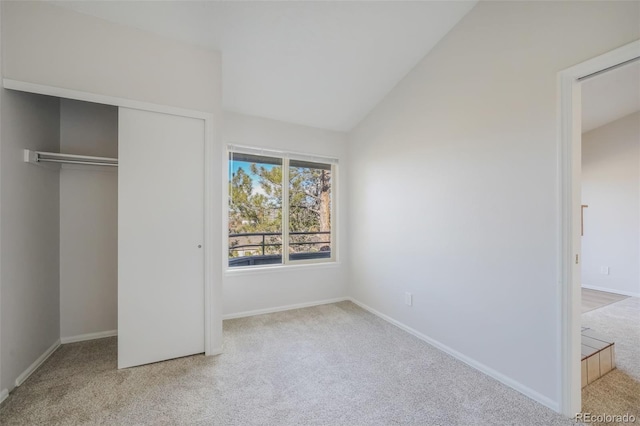 unfurnished bedroom with light colored carpet, vaulted ceiling, and a closet