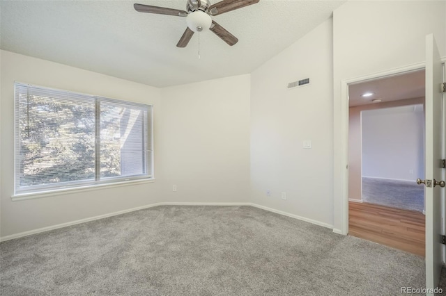 empty room featuring carpet flooring, vaulted ceiling, and ceiling fan