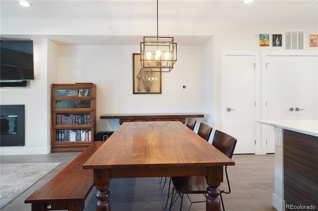 dining area featuring crown molding, a notable chandelier, and light hardwood / wood-style floors