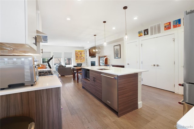 kitchen featuring dishwasher, light hardwood / wood-style floors, an island with sink, sink, and white cabinets