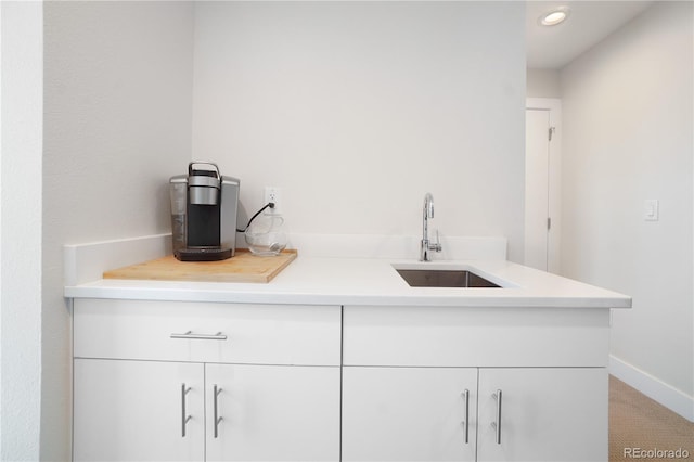 bar featuring carpet flooring, white cabinetry, and sink