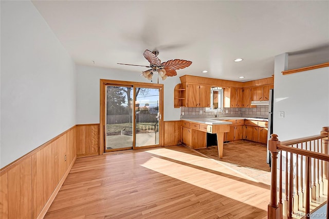 kitchen with decorative backsplash, kitchen peninsula, ceiling fan, sink, and light hardwood / wood-style flooring