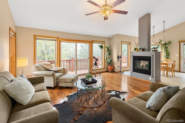 11163 Conifer Mountain Rd, Conifer, CO 80433 - living room featuring vaulted ceiling, ceiling fan, light wood finished floors, and a glass covered fireplace