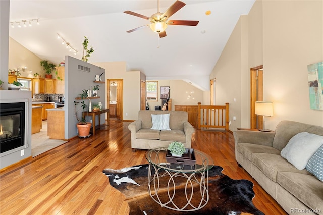 11163 Conifer Mountain Rd, Conifer, CO 80433 - living area with ceiling fan, light wood finished floors, high vaulted ceiling, rail lighting, and a glass covered fireplace