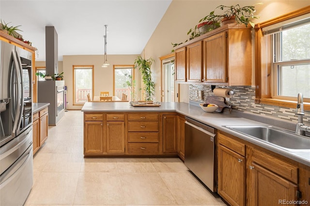 11163 Conifer Mountain Rd, Conifer, CO 80433 - kitchen featuring stainless steel appliances, a peninsula, backsplash, brown cabinetry, and lofted ceiling