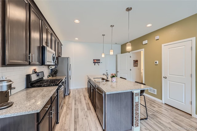 kitchen featuring dark brown cabinets, decorative backsplash, stainless steel appliances, and a sink