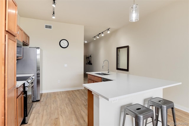 kitchen with electric stove, sink, hanging light fixtures, kitchen peninsula, and a breakfast bar