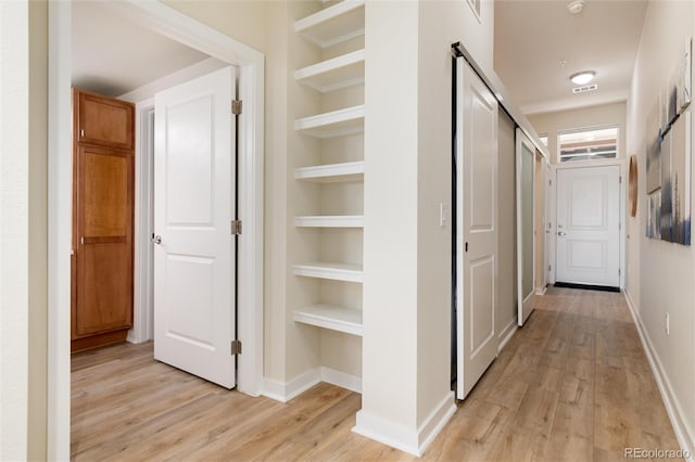 hallway featuring light wood-type flooring and built in shelves