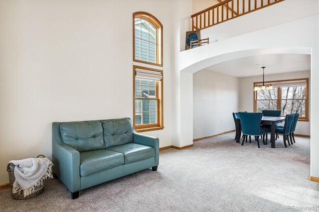 sitting room with a towering ceiling, a chandelier, and carpet flooring