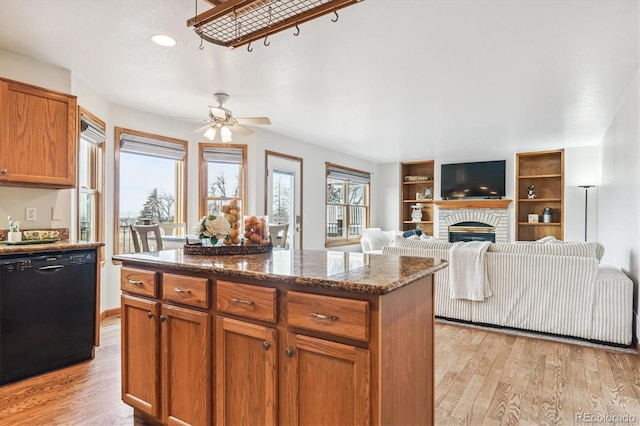 kitchen featuring light hardwood / wood-style flooring, dark stone countertops, dishwasher, a kitchen island, and ceiling fan