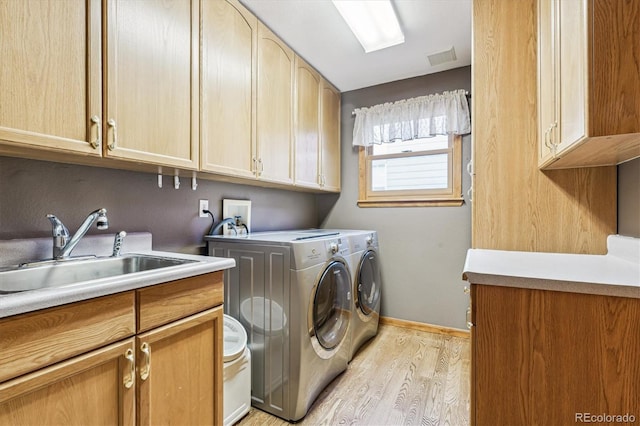 laundry room featuring sink, light hardwood / wood-style flooring, cabinets, and independent washer and dryer