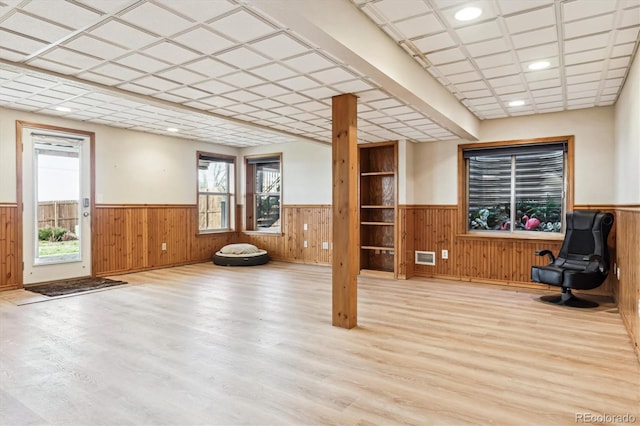 interior space with plenty of natural light, wooden walls, and light wood-type flooring