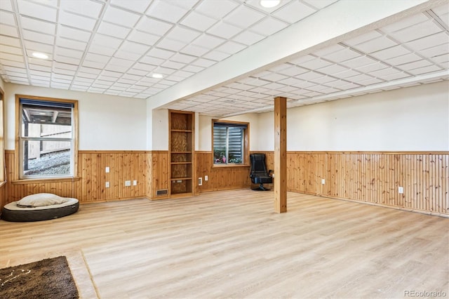 basement featuring wooden walls and light hardwood / wood-style floors