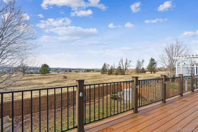 deck with a rural view and a pergola