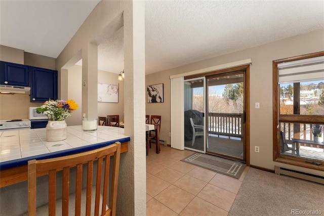 kitchen with a textured ceiling, tile counters, light tile patterned floors, blue cabinets, and a baseboard radiator