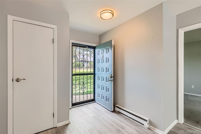 entrance foyer with a baseboard heating unit, light wood-type flooring, and baseboards