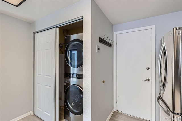 laundry area with estacked washer and dryer and baseboards