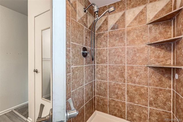 bathroom with tiled shower and baseboards