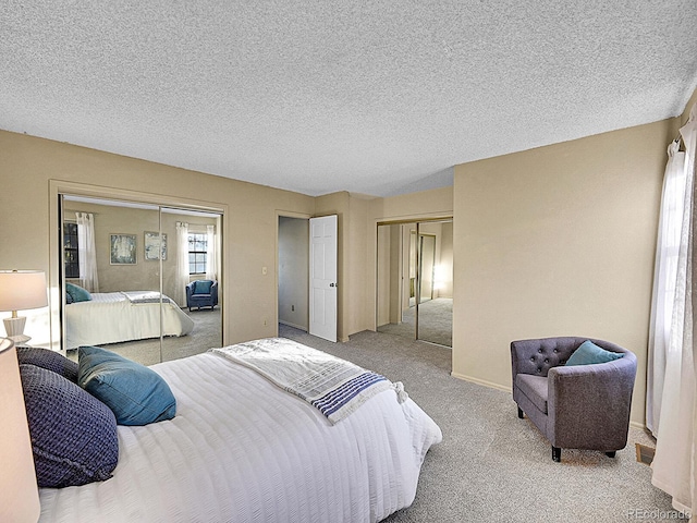 carpeted bedroom with a textured ceiling and two closets