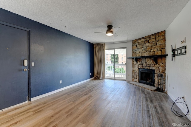 8555 Fairmount Dr Unit C202, Denver, CO 80247 - unfurnished living room featuring a ceiling fan, wood finished floors, a textured ceiling, a stone fireplace, and baseboards