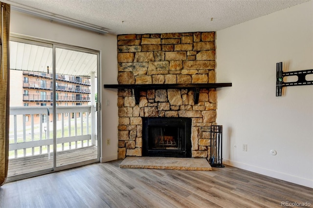 8555 Fairmount Dr Unit C202, Denver, CO 80247 - unfurnished living room featuring a textured ceiling, wood finished floors, a fireplace, and baseboards