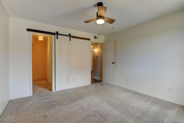 8555 Fairmount Dr Unit C202, Denver, CO 80247 - unfurnished bedroom featuring carpet floors, a spacious closet, a barn door, a textured ceiling, and a ceiling fan