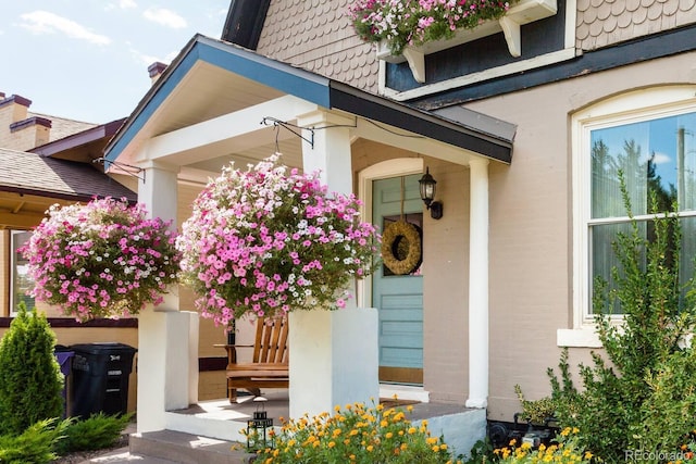 view of exterior entry with covered porch and stucco siding