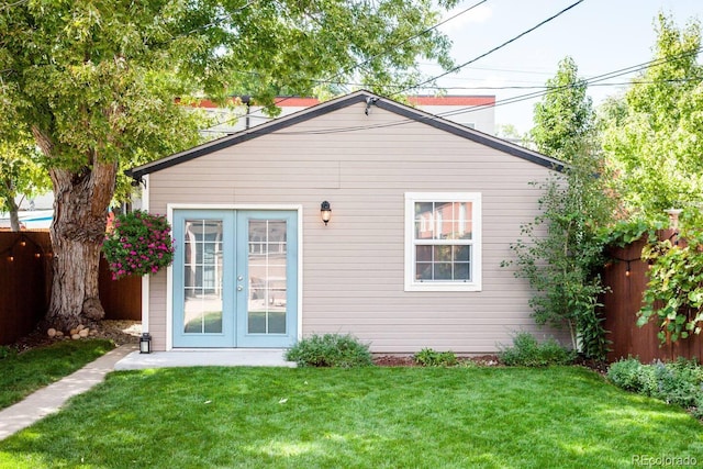 rear view of house featuring a fenced backyard, a lawn, and french doors