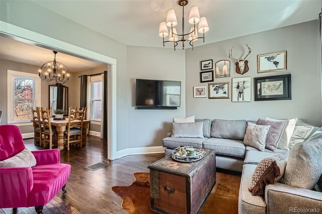 living room featuring baseboards, a chandelier, and dark wood finished floors