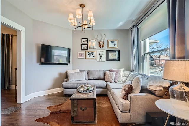 living area with visible vents, a notable chandelier, baseboards, and wood finished floors