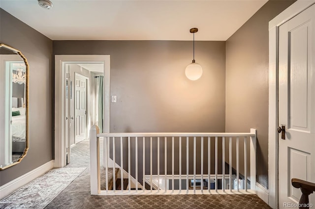 hall with carpet, an upstairs landing, and baseboards