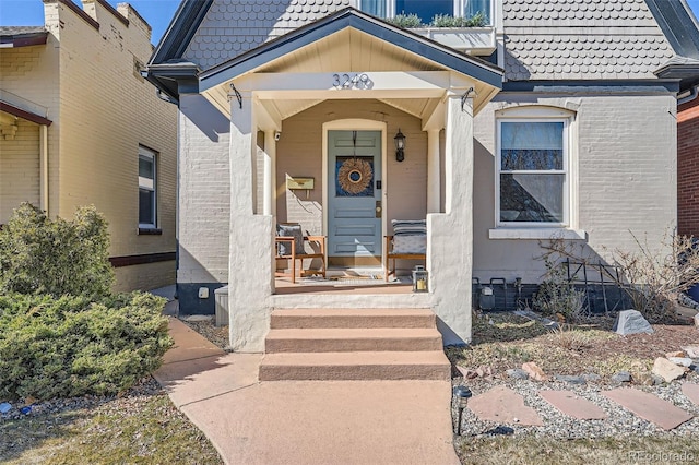 view of exterior entry with covered porch and a tiled roof