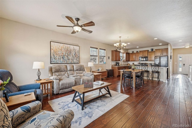 living room with dark hardwood / wood-style flooring and ceiling fan with notable chandelier