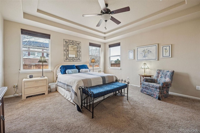 bedroom with carpet flooring, ceiling fan, multiple windows, and a tray ceiling