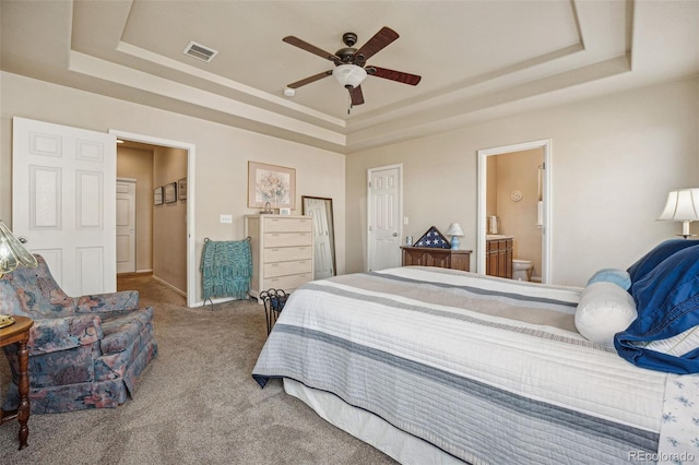 bedroom with ensuite bath, ceiling fan, carpet floors, and a tray ceiling