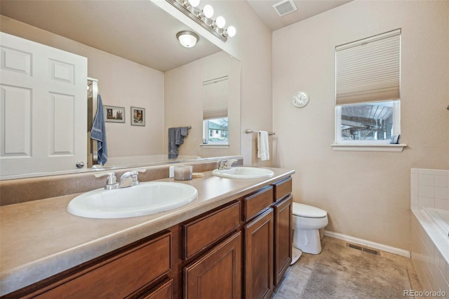 bathroom with tile patterned flooring, vanity, toilet, and tiled tub