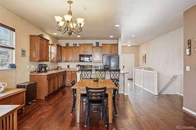 kitchen featuring sink, dark hardwood / wood-style floors, hanging light fixtures, and black appliances