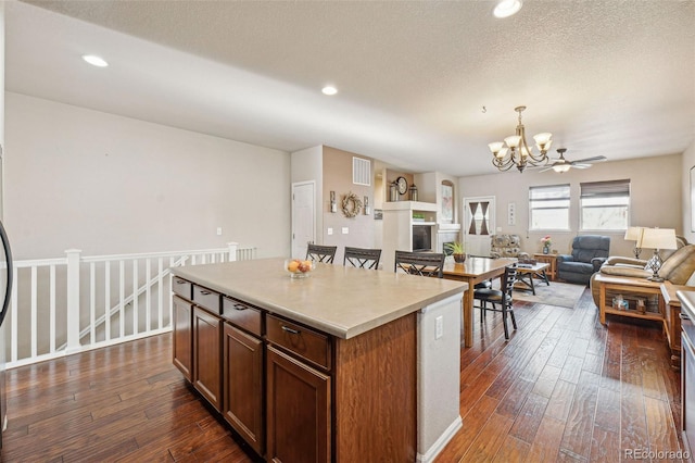 kitchen with a textured ceiling, dark hardwood / wood-style flooring, a center island, and decorative light fixtures