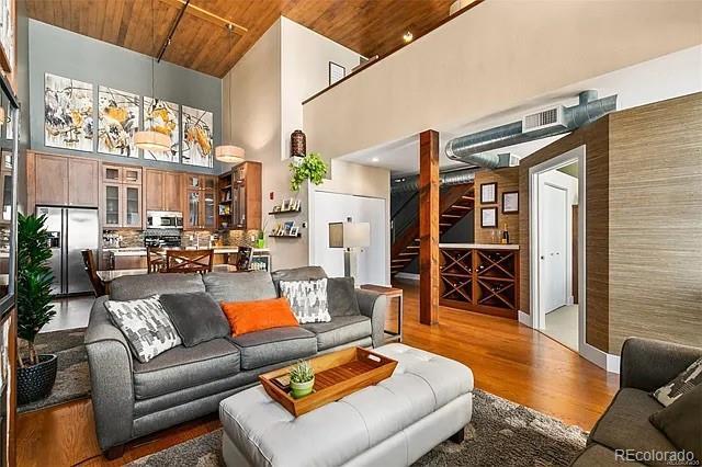 living room featuring a towering ceiling, wood-type flooring, and wooden ceiling