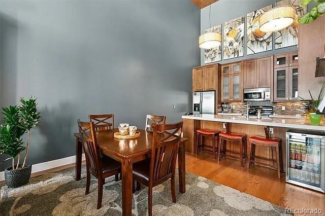 dining area featuring a high ceiling, dark hardwood / wood-style floors, sink, and wine cooler