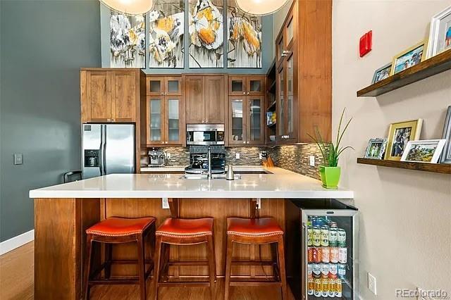 kitchen with wine cooler, stainless steel appliances, kitchen peninsula, and tasteful backsplash