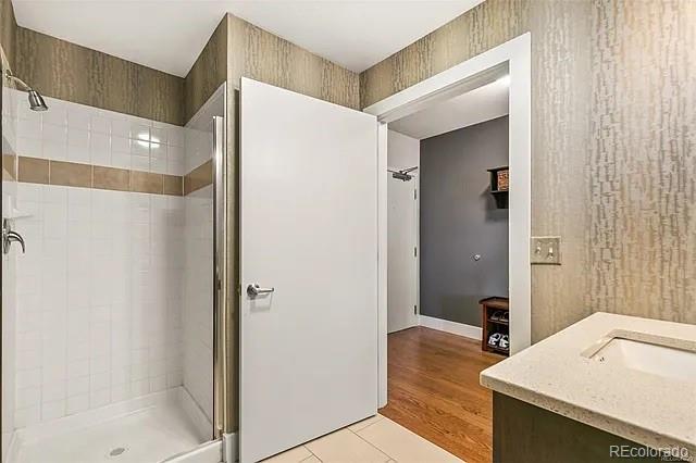 bathroom featuring vanity, a tile shower, and tile patterned floors