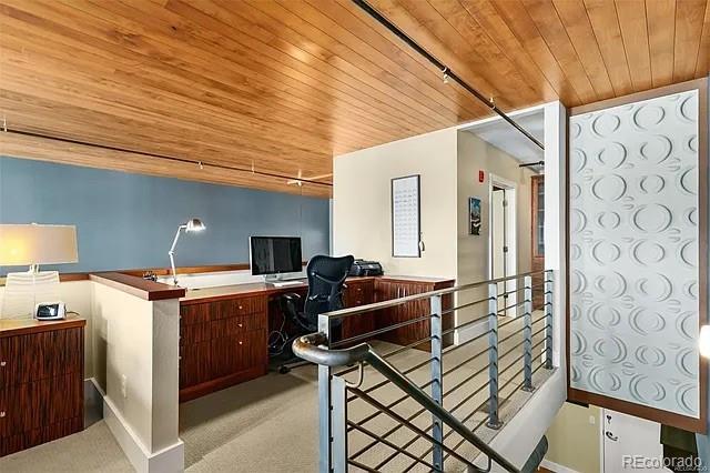 carpeted office featuring built in desk and wood ceiling