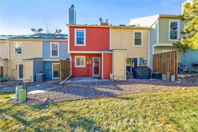 rear view of property with a yard, fence, and central AC unit