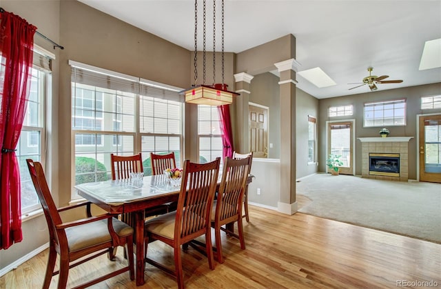 dining space featuring light hardwood / wood-style flooring, ornate columns, a fireplace, and ceiling fan