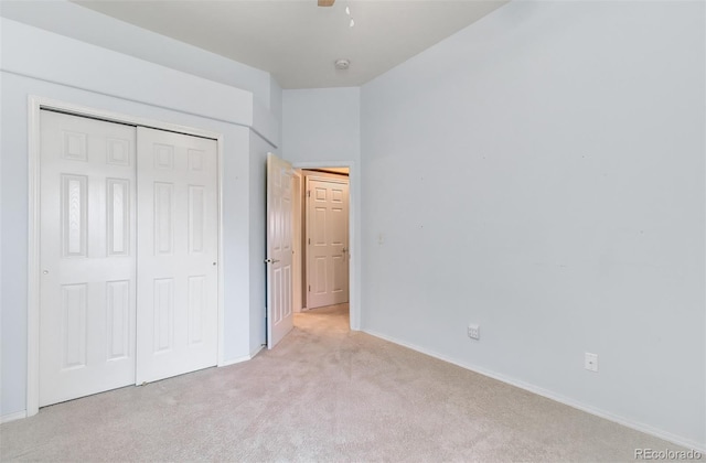 unfurnished bedroom with light colored carpet, a closet, and ceiling fan