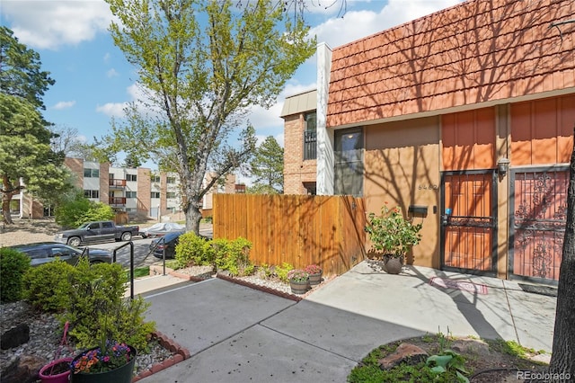 view of property exterior featuring fence, a gate, and mansard roof