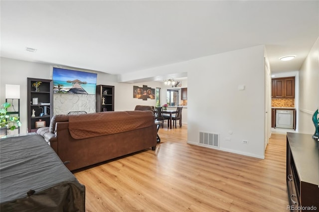 living area with light wood-type flooring, a chandelier, and baseboards